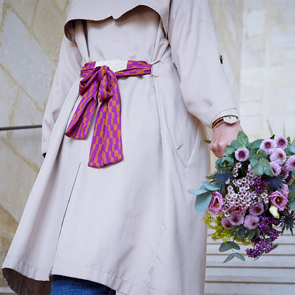 Bandeau ceinture en tissu au style rétro rose et orange noué dans le dos d'un trench beige