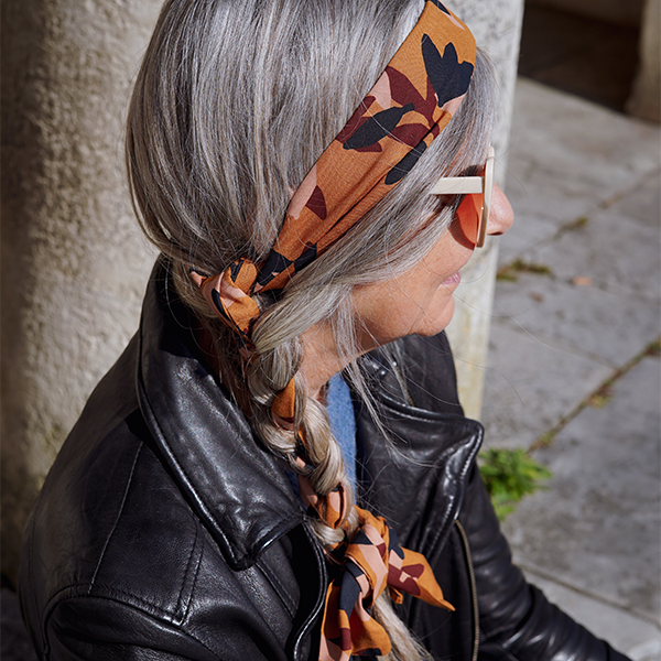 Bandeau en tissu aux couleurs automnales noué dans des cheveux gris avec une tresse