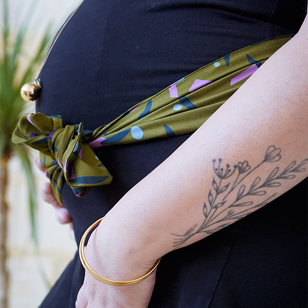 Bandeau ceinture vert kaki qui est noué sur une robe noire autour du ventre d'une femme enceinte 